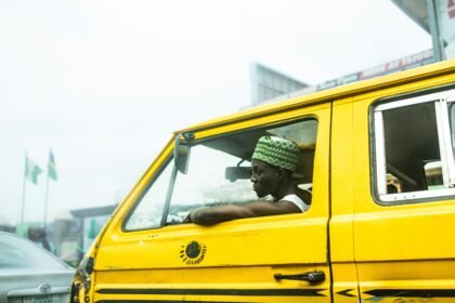 A yellow danfo bus driving down a busy Lagos street