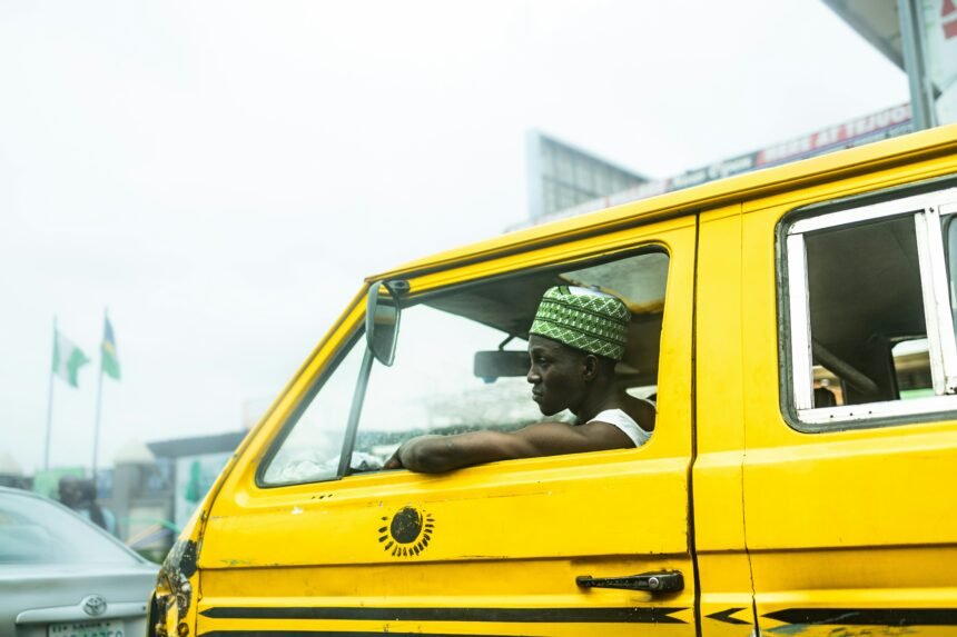 A yellow danfo bus driving down a busy Lagos street